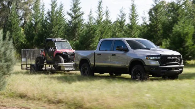 2025 Ram 1500 Rebel towing trailer through grass